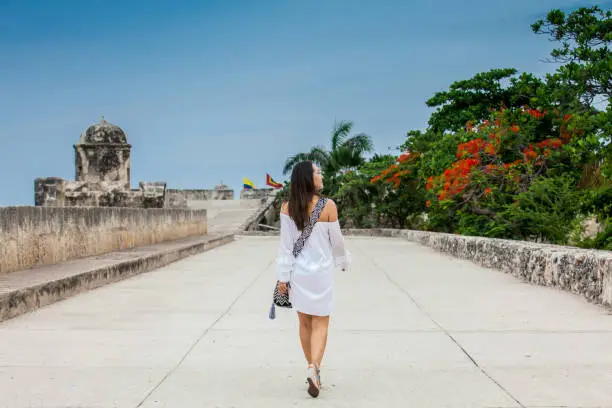 Beautiful woman on white dress walking alone at the walls surrounding the colonial city of Cartagena de Indias