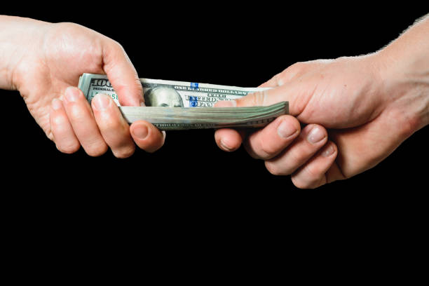 istock The hand, giving money, is isolated on a black background. 1154818667
