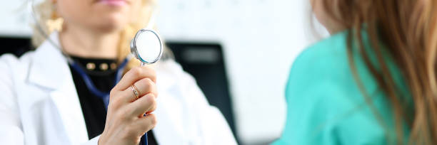 istock Blond mature gp hold stethoscope head in hand while diagnosing little girl 1154821141