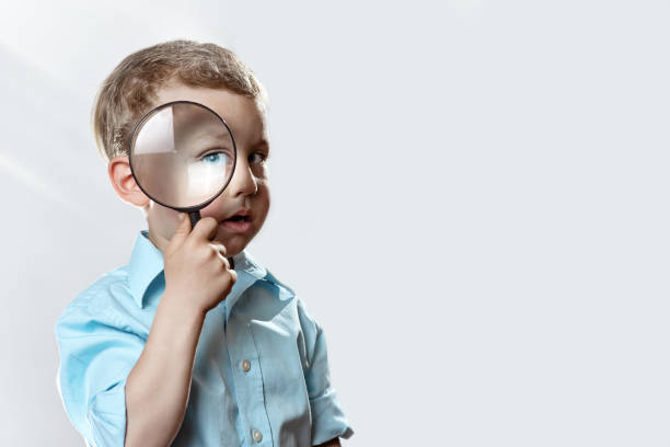 istock boy in a light t-shirt looking into a large magnifying glass 1154822968
