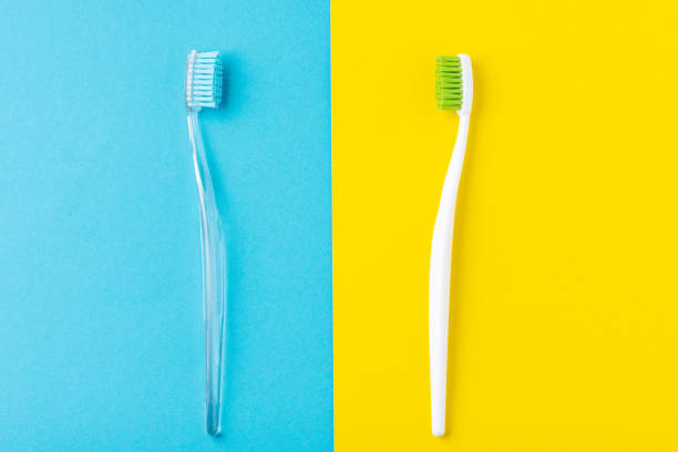istock Two plastic toothbrushes on a pastel blue and yellow  background, flat lay style 1154823219
