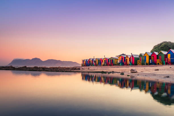 View of the beautiful sunset over False Bay from Kalkbay with little coloured houses on the beach, with mountains in the background, Cape Town, South Africa stock photo