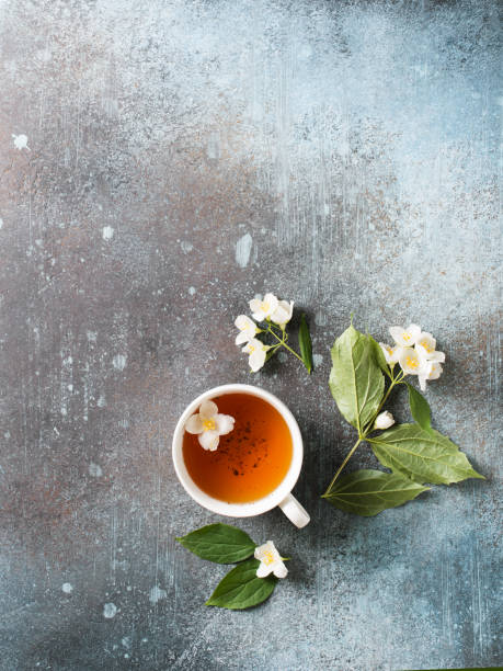 istock Tea jasmine background with teapot, leaves and flowers on dark texture 1154831478