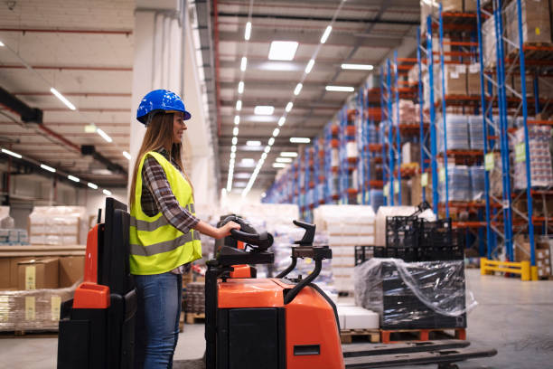 istock Woman warehouse worker operating forklift machine in large distribution warehouse center. 1154831745