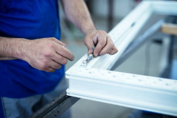 istock Manual worker assembling hinge on PVC doors and windows. Workshop for aluminum and PVC windows and doors production. 1154833931
