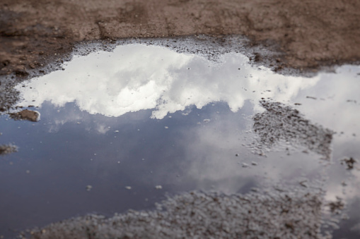 A cloud reflection in a puddle of muddy water.