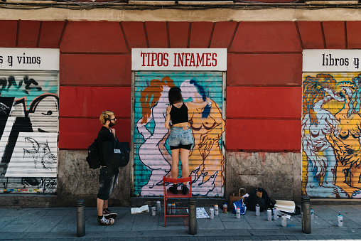 Madrid, Spain - June 9, 2019: Artist painting storefront in Malasana district in Madrid during Graffiti Festival. Malasana is one of the trendiest neighborhoods in Madrid