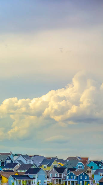 istock Panorama frame Panoramic view of houses under vast sky filled with illuminated puffy clouds 1154837901