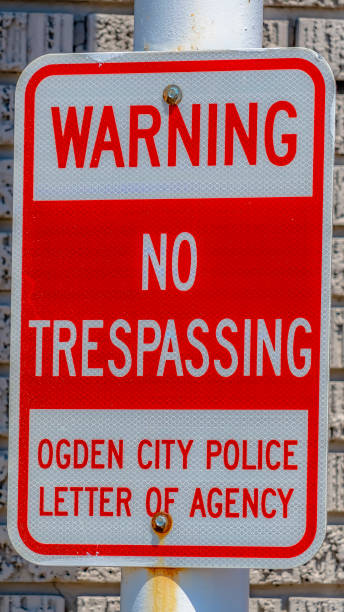 istock Vertical tall frame Warning No Trespassing sign against a metal pole and rough brick wall 1154838018