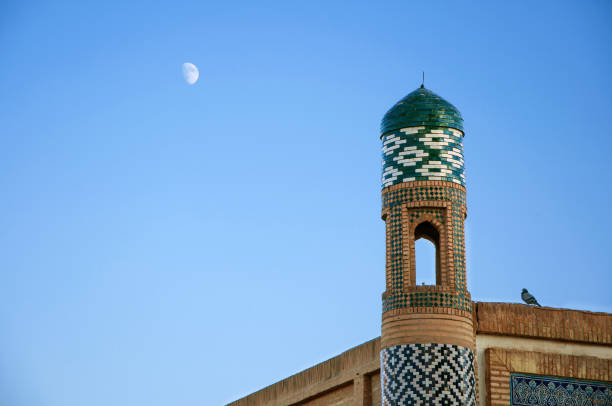 istock Islamic tower over blue sky and moon with pigeon, sitting on the wall 1154839079