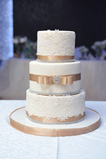 Beautiful three-tiered wedding cake decorated with mastic and beige ribbons. Close up