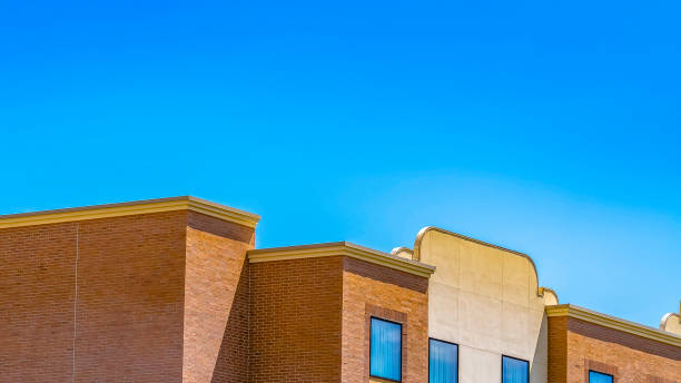 istock Panorama frame Trees with bright green foliage against a residential building with brick wall 1154845052