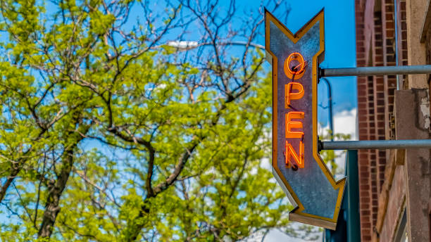 istock Panorama frame Open arrow sign on a building with vibrant trees and blue sky in the background 1154845076