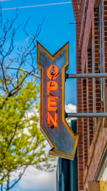 istock Panorama frame Lamp post and building with an Open sign against vibrant trees on a sunny day 1154845144