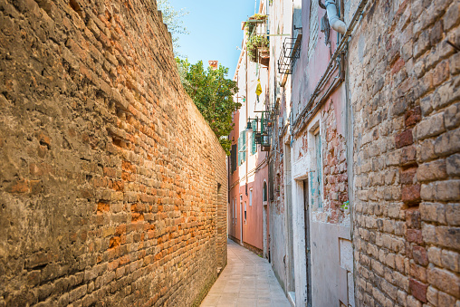 Old narrow street with brick houses in Venice, Italy