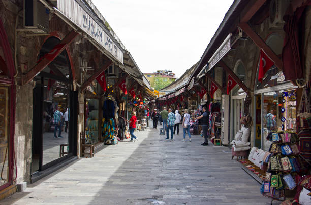 Istanbul, Turkey - May 5, 2019: Turkish shopkeepers and people in middle of the shop's lane playing board game while tourists are busy shopping at Arasta Bazaar complex adjacent to Blue Mosque in Sultanahmet District, Istanbul. Arasta bazar was built at the same time as the Blue Mosque and functioned as a market area, the rents of which went towards the mosque's upkeep.