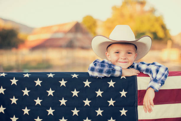 młody kowboj z amerykańską flagą - cowboy cowboy hat hat summer zdjęcia i obrazy z banku zdjęć
