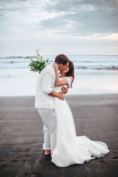 istock Elegant gorgeous bride and groom walking on ocean beach during sunset time. 1154854258