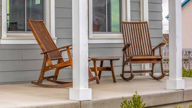 istock Panorama frame Front porch of a house with brown rocking chairs and rectangular white pillars 1154854558