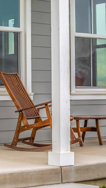 istock Panorama Front porch of a house with brown rocking chairs and rectangular white pillars 1154854603