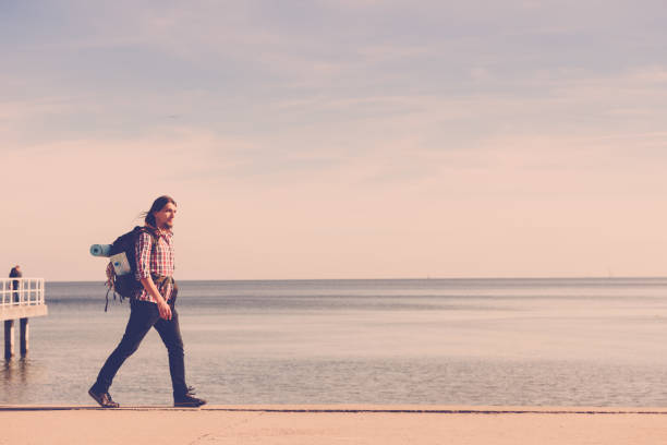 istock Man hiker with backpack tramping by seaside 1154861647