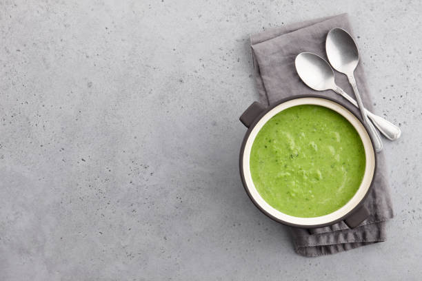 Fresh pea soup in bowl with spoons and napkin
