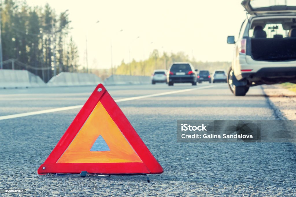 Broken car on the side of the highway and an emergency stop sign Broken car on the side of the highway and an emergency stop sign. Vehicle Breakdown Stock Photo