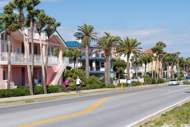 village de ville de plage de miramar avec des maisons colorées multicolores jaunes en bord de mer en floride panhandle golfe du mexique, rue de route d’autoroute de côte - senior couple cycling beach bicycle photos et images de collection