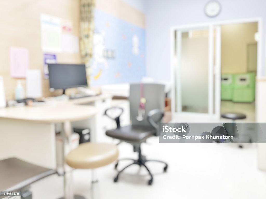 Blur abstract background inside empty patient examination room with bed in OPD ward. Blurry doctor desk for diagnosis sick people working space in hospital. Defocused interiors healthcare work place Doctor Stock Photo