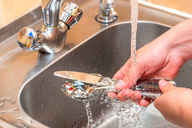 manos cerca-lavar los cubiertos bajo el agua corriente en la cocina - silverware clean wet kitchen utensil fotografías e imágenes de stock