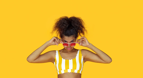 Fashion young african girl black woman wear stylish pink sunglasses glasses looking at camera isolated on summer yellow studio background, horizontal banner for website design, portrait, copy space