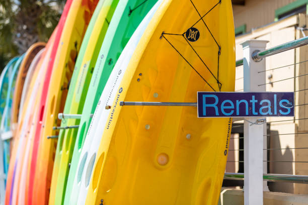 gros plan de la location signent avec des bateaux colorés de kayak et de planche de surf dans le village urbain de ville sur la promenade de port en floride panhandle golfe du mexique - canoe kayak, jaune photos et images de collection