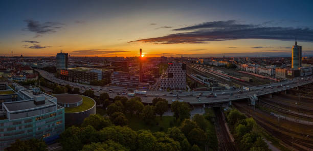 Munich from above at a beautiful sunrise. The red sun next to the famous Frauenkirche by the view from the Donnersberger Bruecke with traffic made by drone.