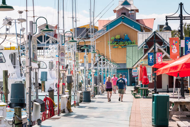 Harborwalk village, people walking by marina with Margaritaville restaurant tropical bar cafe on summer sunny day in Florida Panhandle Destin, USA - April 24, 2018: Harborwalk village, people walking by marina with Margaritaville restaurant tropical bar cafe on summer sunny day in Florida Panhandle harborwalk stock pictures, royalty-free photos & images