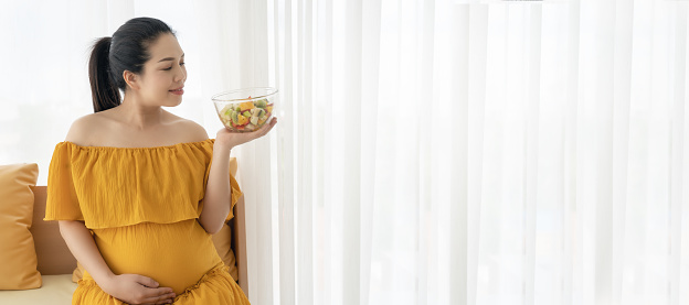 Beautiful Asian pregnant women are enjoying eating fruit and vegetable salads.
