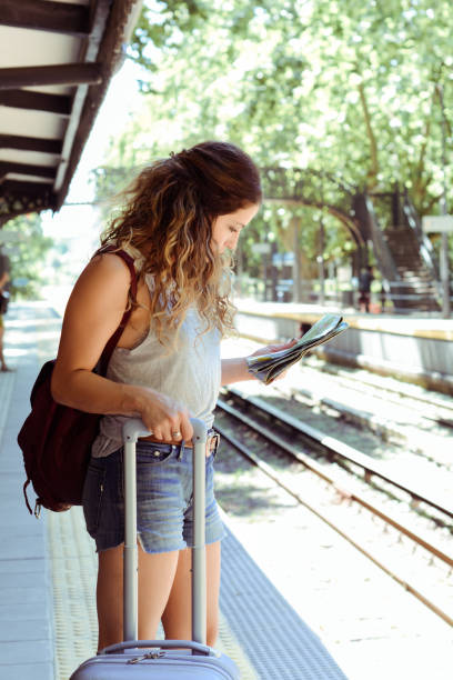 istock Woman with suitcase waiting the train. 1154890410