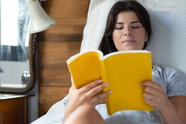 istock woman laying in bed and reading book 1154890435