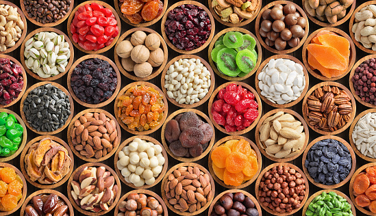 mixed nuts and dried fruits in bowls, top view. healthy snack for vegetarian, food background.