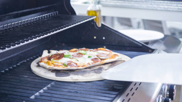 istock Cooking pizza on outdoor gas grill. 1154901104
