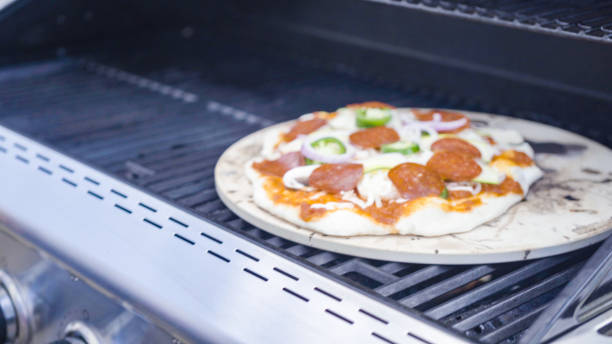 istock Cooking pizza on outdoor gas grill. 1154901419