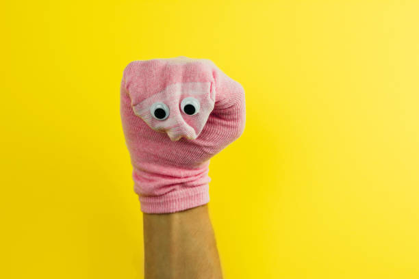 divertido calcetín de muñeca con ojos googly sobre un fondo amarillo - offbeat fotografías e imágenes de stock