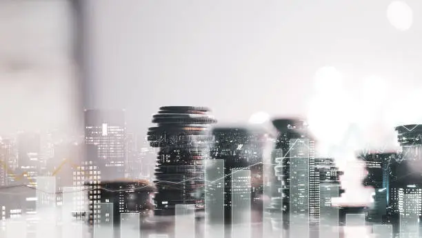 Photo of Double exposure of city view. diagram graph and rows of money coins for finance , money , investment and business concept background