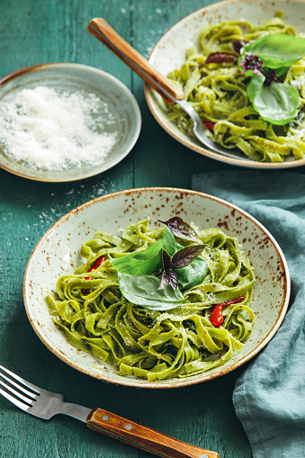 Vegetarian spinach pasta with rocket and basil pesto on green background