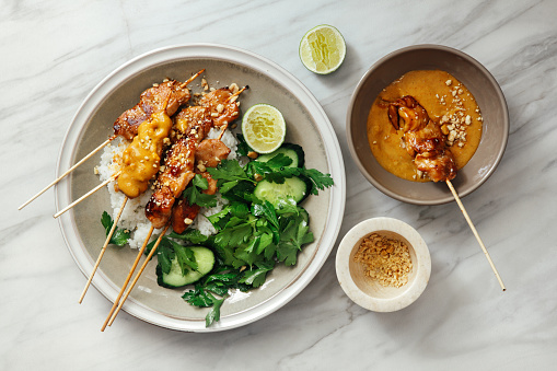 Thai chicken satay with peanut sauce on marble background