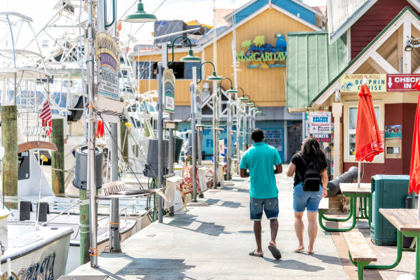 City town Harborwalk village boardwalk at marina with Margaritaville restaurant couple walking on summer day in Florida Panhandle, Gulf of Mexico Destin, USA - April 24, 2018: City town Harborwalk village boardwalk at marina with Margaritaville restaurant couple walking on summer day in Florida Panhandle, Gulf of Mexico harborwalk stock pictures, royalty-free photos & images