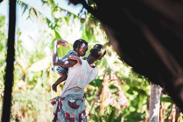 mujer de pueblo africano sosteniendo su bebé en sus brazos - malnourished fotografías e imágenes de stock