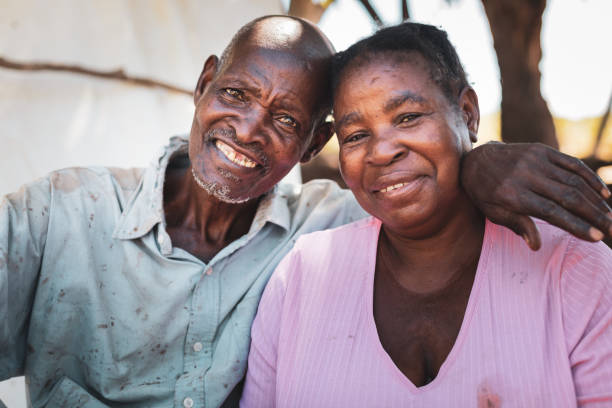 retrato de una pareja africana mayor sentada cerca de su choza en un pueblo - women poverty senior adult mature adult fotografías e imágenes de stock