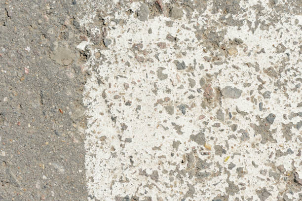 istock Old asphalt surface with white paint on it close up. Abstract background 1154914393