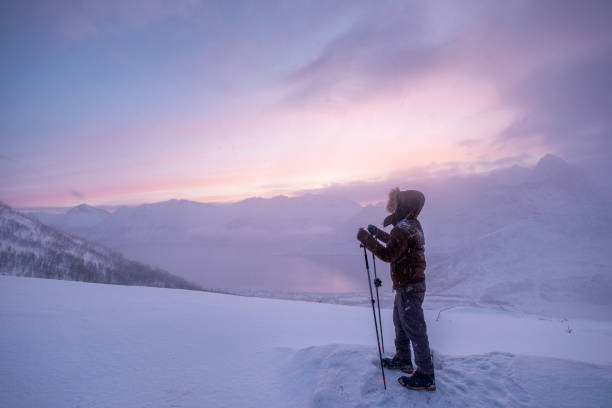 istock Man climber with trekking poles standing on snow mountain peak 1154914517