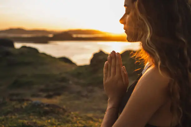 Photo of Woman praying alone at sunrise. Nature background. Spiritual and emotional concept. Sensitivity to nature